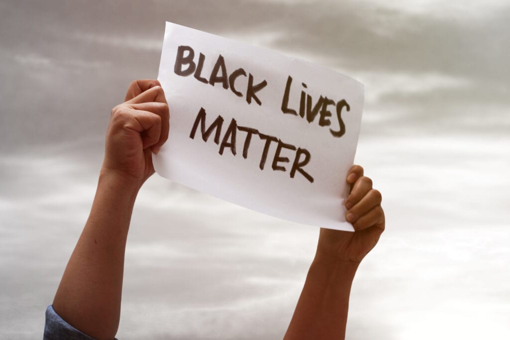 Why Black Lives Matter - hands holding a black lives matter sign in the sky