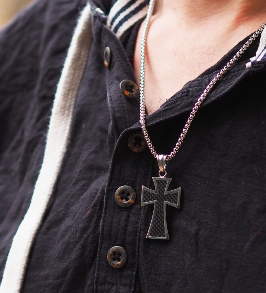 Trend Him Byzantine cross necklace. Close up on necklace on a man with a black top. 